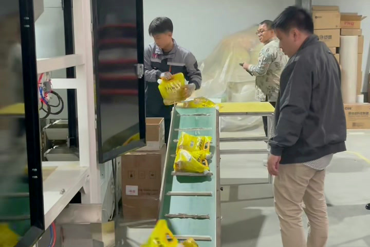 People beside packaging equipment inspecting sample pouches on the output conveyor