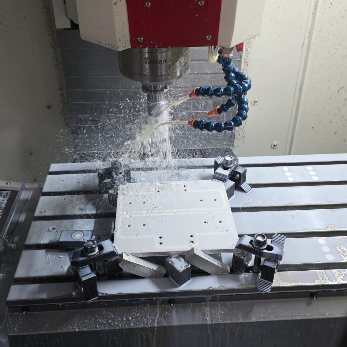 Machining a metal workpiece held in a fixture with coolant at the cutting area