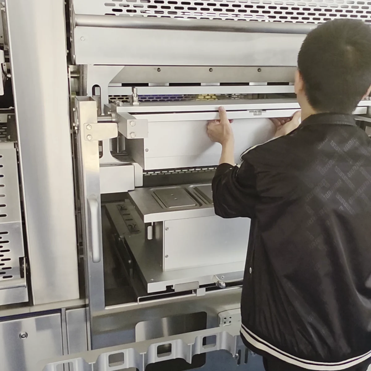 A person adjusting or inspecting an internal packaging machine assembly