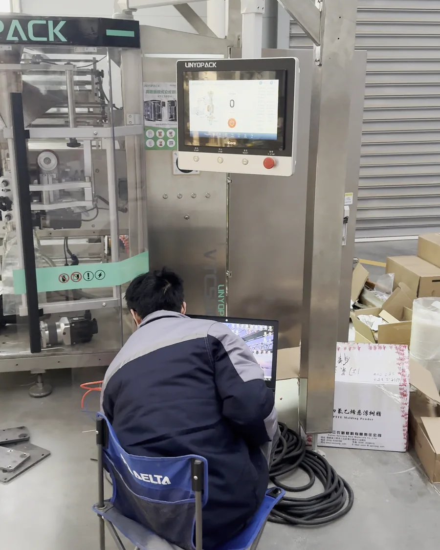 A technician commissioning a packaging machine below its touchscreen.