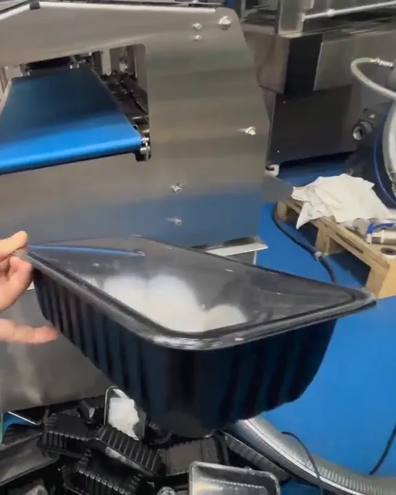 A hand holding a sealed tray beside a T680 tray sealer.
